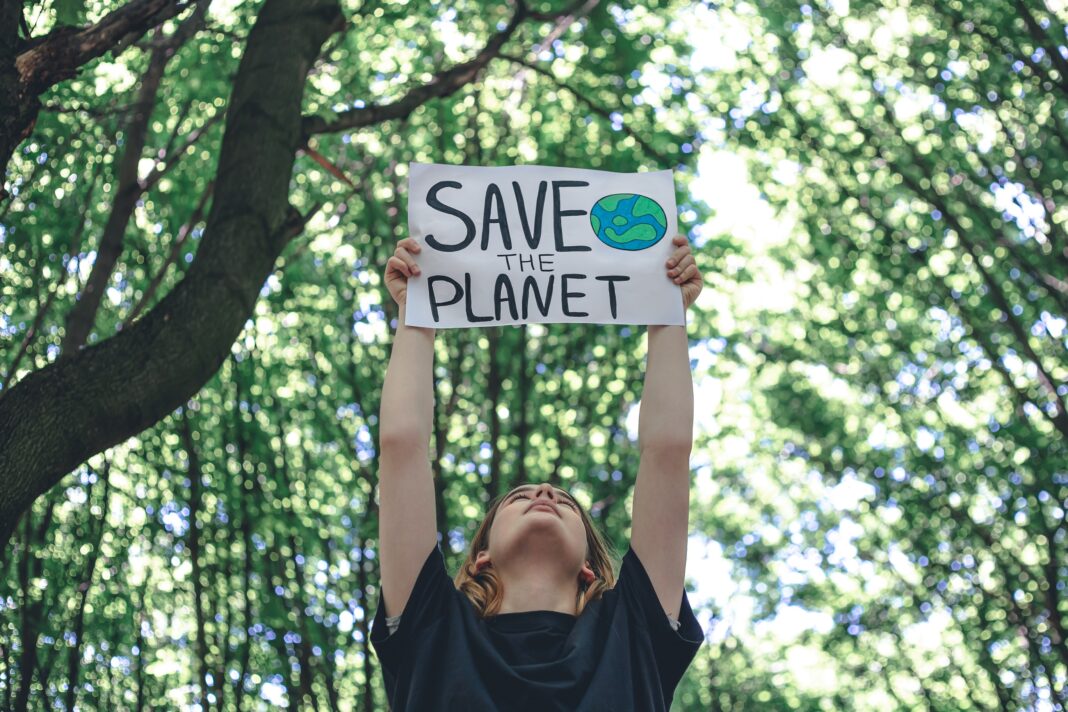 Poster in the call to save the planet in female hands in the forest.